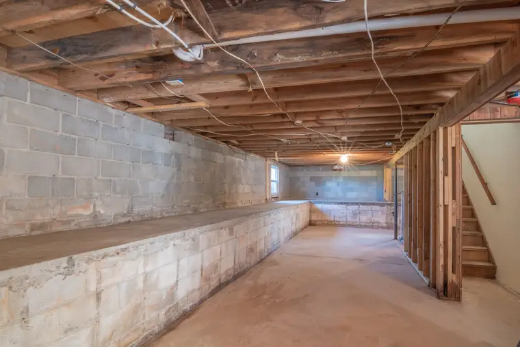 Unfinished basement with exposed joists, block walls, and a bare slab